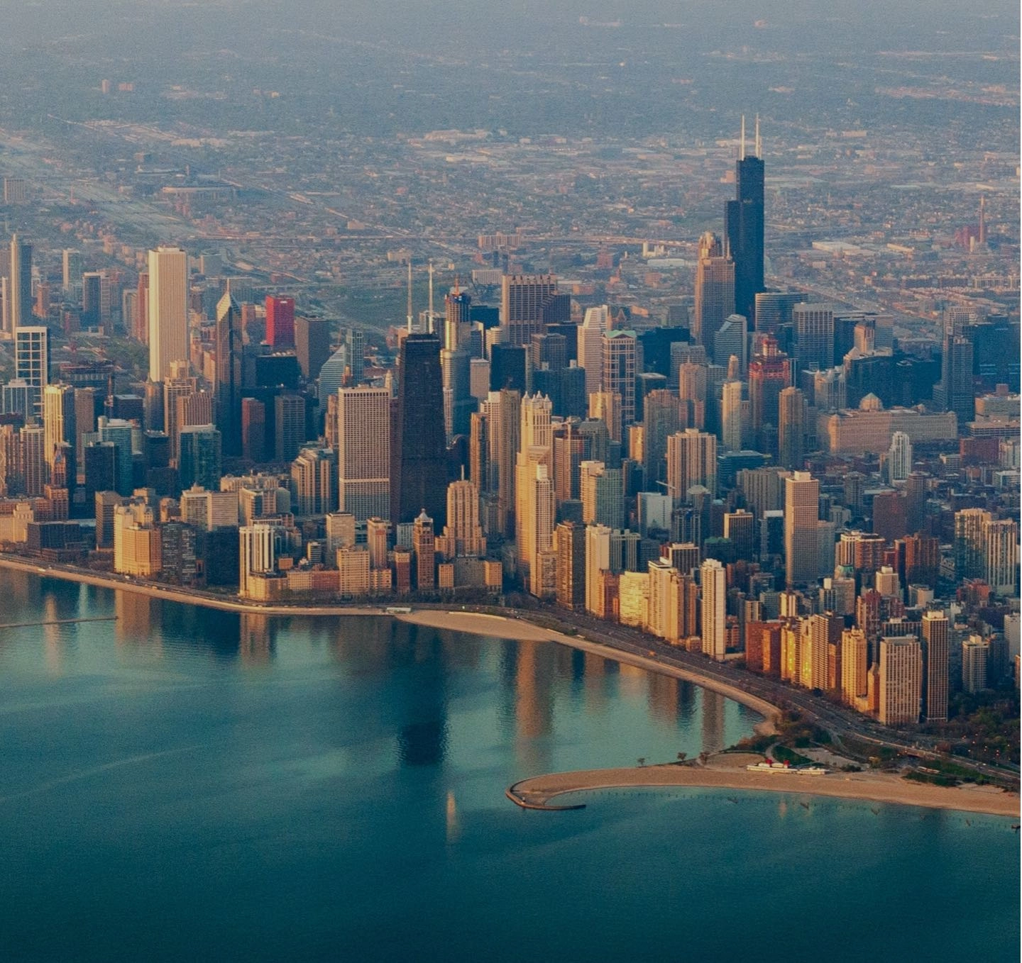 An aerial view of the Chicago skyline along the lakefront at golden hour.